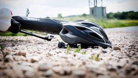 Symbolbild: Ein Fahrrad liegt nach einem Sturz samt Helm auf dem Boden.