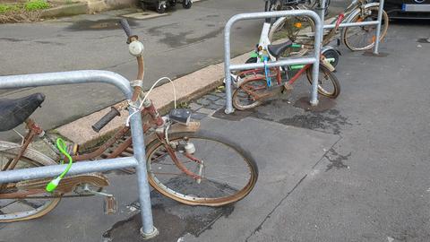 Drei rostige Fahrräder lehnen an einem Fahrradbügel in der Hansastraße in Kassel