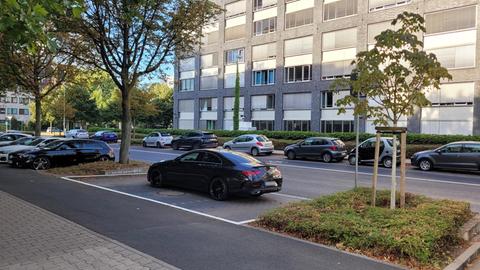 Eine schwarze Limousine belegt drei Parkplätze an einer Straße, im Hintergrund ist das Frankfurter Polizeipräsidium zu sehen.