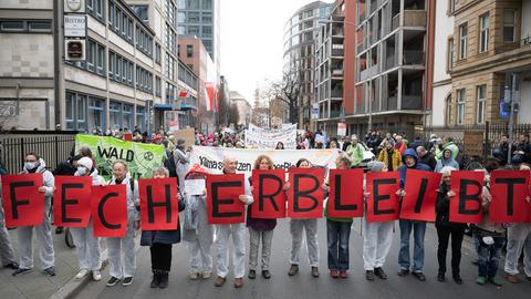 Teilnehmer halten während einer Demonstration für den Erhalt des Fechenheimer Waldes und gegen den Bau des Riederwaldtunnels mit Schildern, auf denen zusammen steht "Fecher bleibt" hoch. 