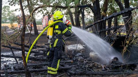 Feuerwehr, die Wasser auf verkohltes Holz spritzt.