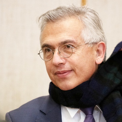 Peter Feldmann wirft sich lächelnd einen Schal um.