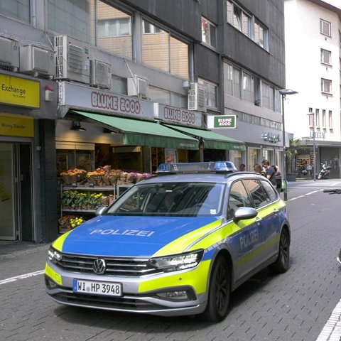 Ein Polizeiauto steht in einer Fußgängerzone.
