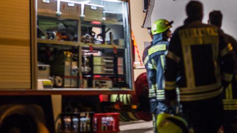 Feuerwehreinsatz: Drei Männer in Feuerwehrkleidung stehen neben einem Feuerwehrfahrzeug mit geöffneter Klappe