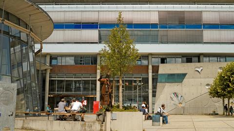 Studenten sitzen vor Gebäuden der Frankfurter Fachhochschule
