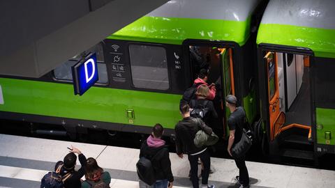 Reisende steigen in einem Bahnhof in einen Zug des Unternehmens Flixtrain.