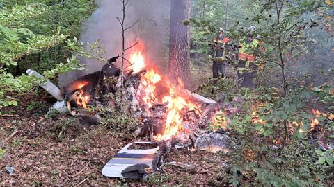 Das abgestürzte Flugzeug steht in Flammen in einem Wald.