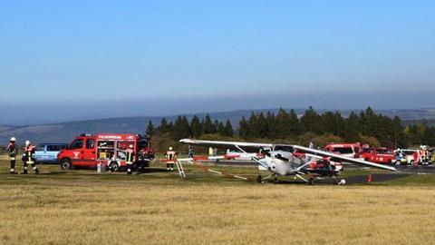 Das Unglücksflugzeug vom Typ Cessna  am Ende einer Landebahn, Einsatzkräfte