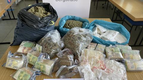 Beschlagnahmte Drogen und Bargeld - die Drogen in Plastiksäcken, das Geld bündelweise, dazu ein Schild Polizeidirektion Bergstraße