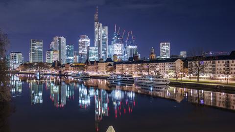 Die Frankfurter Wohngebäude und Bürohochhäuser spiegeln sich im Main. 