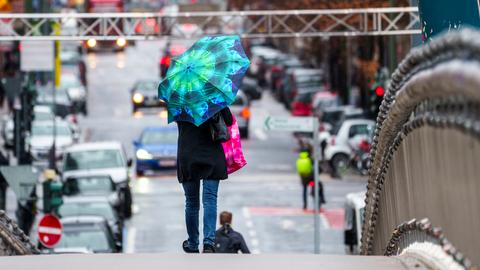 Eine Frau geht mit einem Regenschirm über eine Brücke