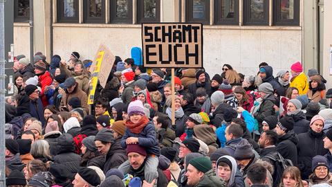 Protestierende Menschen halten Schilder hoch: "Schämt euch" steht auf einem.