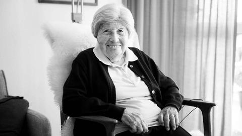 Trude Simonsohn sitzt in einem Sessel und lächelt in die Kamera. Das Foto ist in schwarz-weiß gehalten.