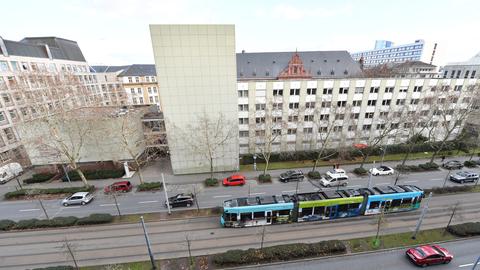 Eine Straßenbahn fährt an einem Gebäude vorbei.