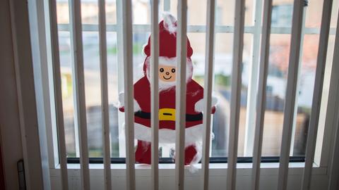 Ein gebastelter Weihnachtsmann klebt in Frankfurt in der Justizvollzugsanstalt im Stadteil Preungesheim hinter und vor den Gittern an einer Fensterscheibe. 
