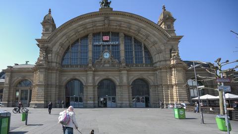 Eine Frau mit Hund geht über den fast menschenleeren Bahnhofsvorplatz des Hauptbahnhofs.