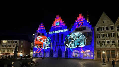 Das Frankfurter Rathaus wird in rot und blau angestrahlt, zu sehen sind zwei Football-Helme und der Schriftzug NFL Frankfurt.