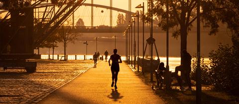 Eine Joggerin läuft kurz nach Sonnenaufgang in Frankfurt am Main entlang