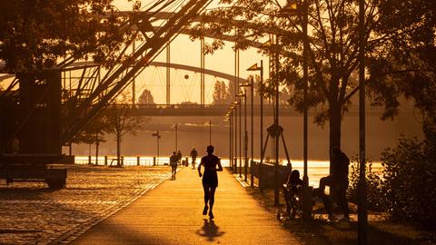 Eine Joggerin läuft kurz nach Sonnenaufgang in Frankfurt am Main entlang