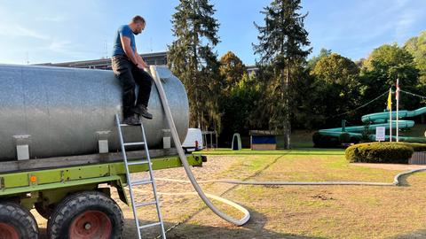 Mit einem 20 Meter langen Feuerwehrschlauch wird Wasser aus dem Becken des Bad Schwalbacher Freibads gepumpt, damit Bauern damit ihre Felder gießen können.