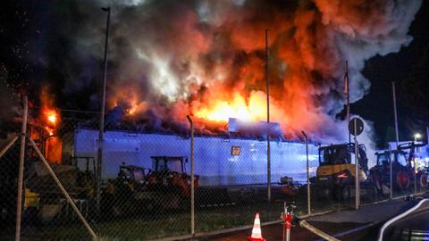 Feuer und Qualm schlagen aus Lagerhalle in dunklen Nachthimmel