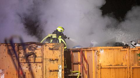 Feuerwehrleute löschen qualmende Container