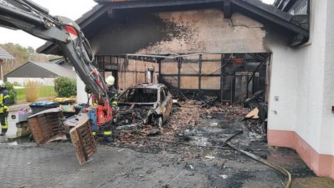 Trümmer der Garage und ein Gerippe eines Autos sind nach dem Brand übrig
