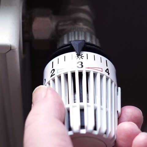 Nahaufnahme einer Hand, die ein Thermostat dreht