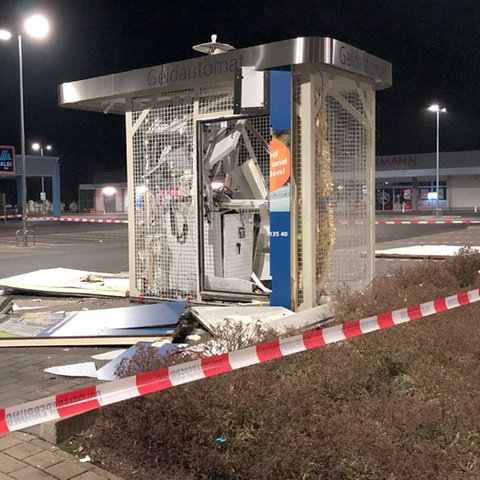 Bildkombo: links ein gesprengter Geldautomat auf einem Supermarktparkplatz, um welchen Metall- und Plastikteile liegen. Rechts eine Hessenkarte mit Punkten und Farbflächen.