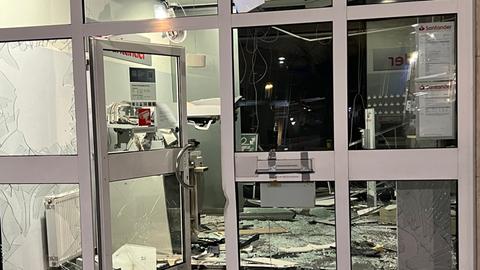 Nach einer Geldautomatensprengung ist der Innenraum einer Bankfiliale stark beschädigt, Glassplitter und Trümmer liegen auf dem Boden.