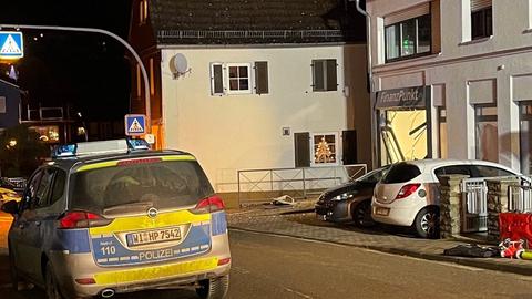 Ein Polizeiauto parkt vor einem Haus, auf dem "Finanzpunkt" steht. Unter diesem Schriftzug sind Teile des Fensters herausgerissen.