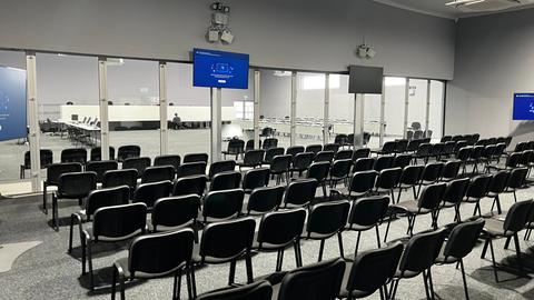 Eine Halle mit Zuschauer-Stühlen, im Hintergrund mit einer Glaswand abgetrennt der Gerichtsbereich