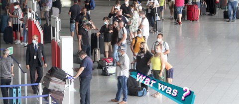 Foto: Blick von oben auf eine Menge von Reisenden, die mit ihrem Gepäck in einer langen Schlange stehen. Auf dem Bild eine kleine, farbige Grafik mit dem Schriftzug "war was?".