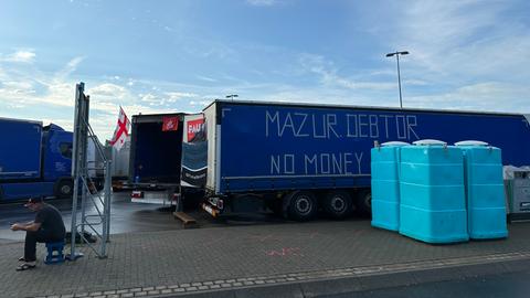 Streikender Lkw-Fahrer sitzt vor einem der Lkw