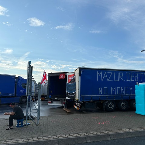 Streikender Lkw-Fahrer sitzt vor einem der Lkw