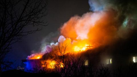 Flammen schlagen aus dem Dach eines Gartenbaubetriebes in Griesheim, Feuerwehrleute versuchen den Brand zu löschen.