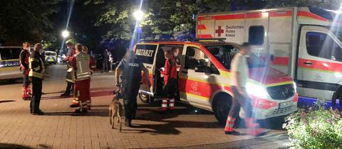 Helfer und Polizisten stehen neben einem Krankenwagen und einem Notarztwagen.
