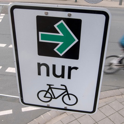Auf einem Verkehrsschild sind ein grüner Pfeil und ein Fahrrad zu sehen.