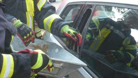 Feuerwehrleute schlagen Autoscheibe ein