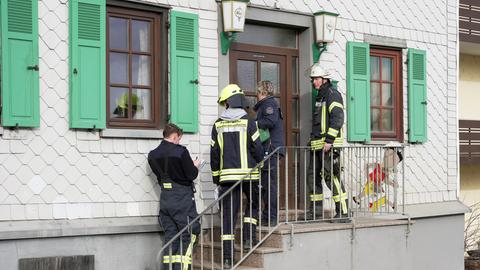 Feuerwehrleute stehen vor einem Haus, einer von ihnen schreibt in einen Notizblock.