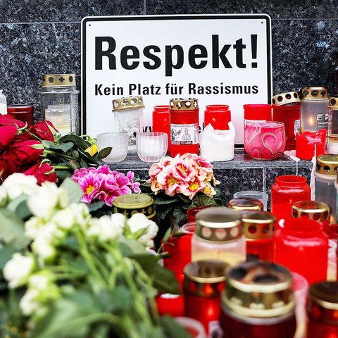 Foto eines Gedenkortes in Hanau mit vielen Kerzen, Blumen und einem Schild: "Respekt! Kein Platz für Rassismus" 