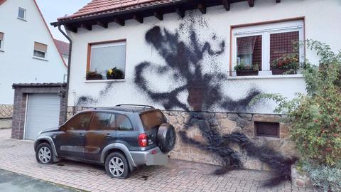 Ansicht eines Hauses, die Fassade ist mit schwarzer Farbe beschädigt