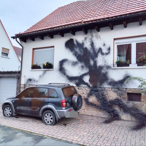 Ansicht eines Hauses, die Fassade ist mit schwarzer Farbe beschädigt