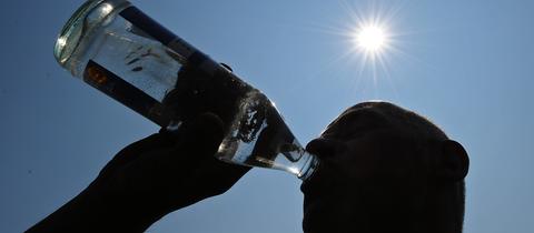 Mann trinkt unter sengender Sonne aus einer Wasserflasche