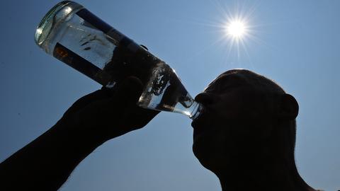 Mann trinkt unter sengender Sonne aus einer Wasserflasche