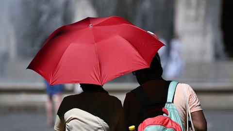 Ein Paar mit Regenschirm zum Sonnenschutz.