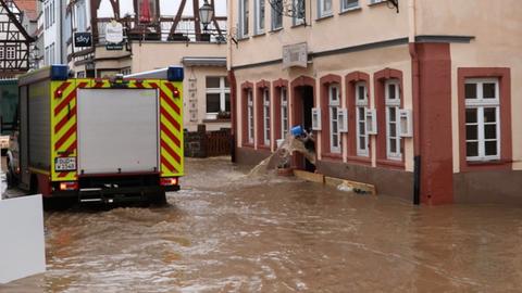 Die Feuerwehr fährt durch eine überschwemmte Straße in der Altstadt von Büdingen.