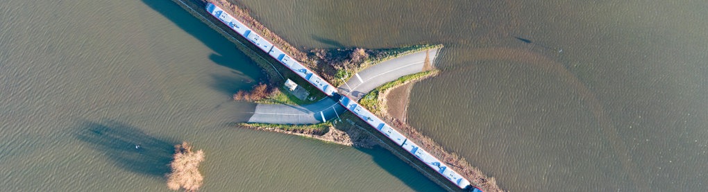 Hochwasser bei Nidderau-Eichen: Ein Zug fährt über eine fast vollständig überflutete Landstraße