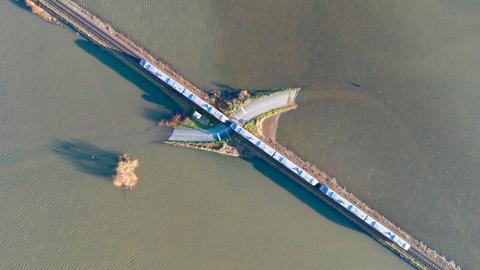 Hochwasser bei Nidderau-Eichen: Ein Zug fährt über eine fast vollständig überflutete Landstraße