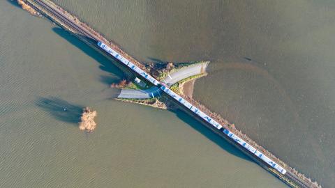 Hochwasser bei Nidderau-Eichen: Ein Zug fährt über eine fast vollständig überflutete Landstraße